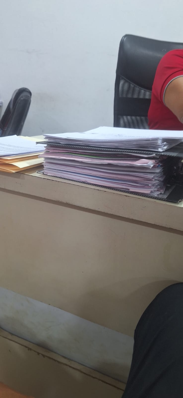 Estoy aca ahora con lo de la solvencia

Stack of documents on a desk with a person's hand and leg visible.